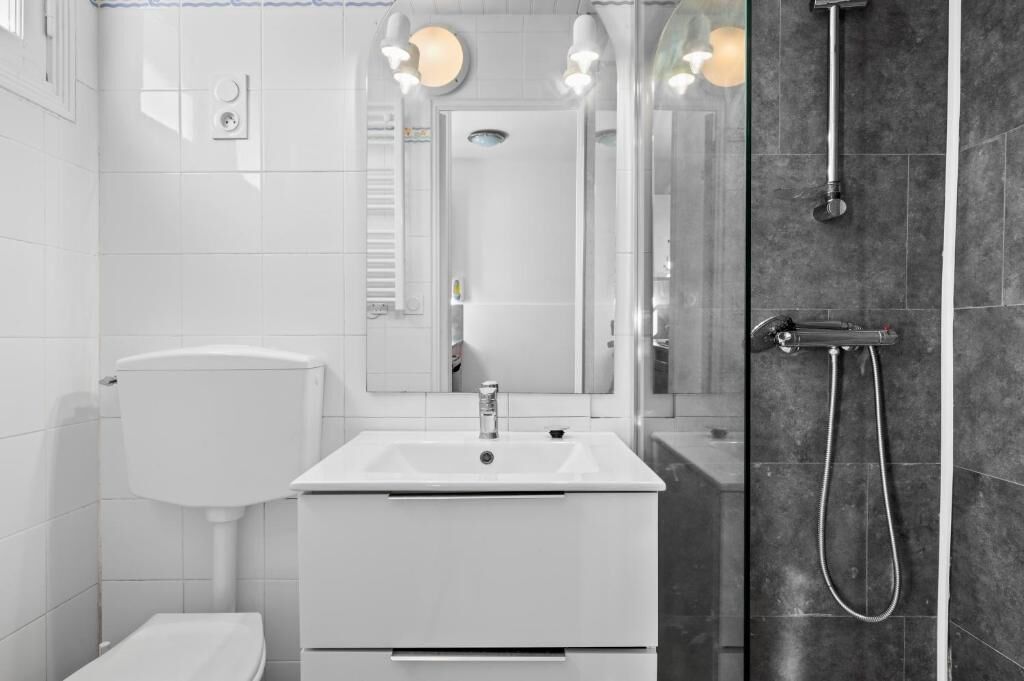 A modern bathroom with a white sink, mirror, and shower.