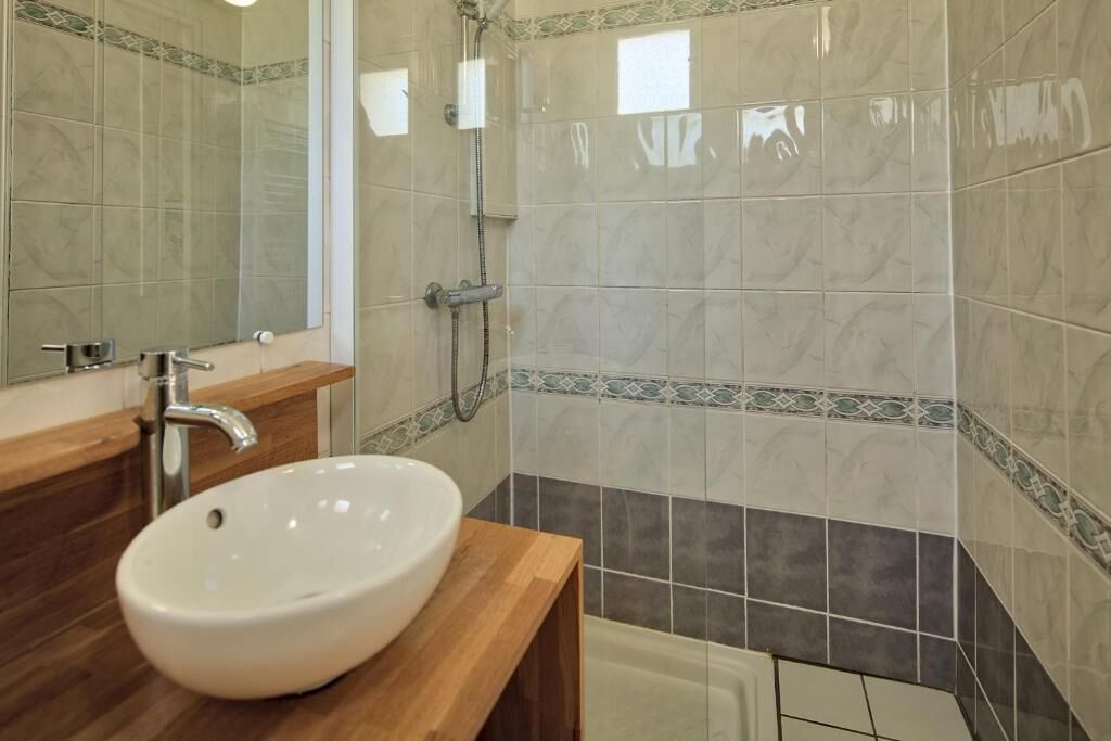 A bathroom with a white sink, a mirror, and a shower.