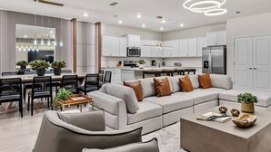 A modern kitchen with white cabinets, stainless steel appliances, and pendant lighting.