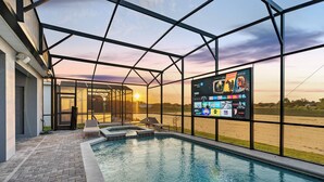 A swimming pool with a glass enclosure, a sunset view, and a digital screen displaying various channels.