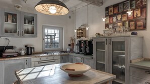 Een keuken met een houten tafel, een groot raam en een muur versierd met oude reclameborden.