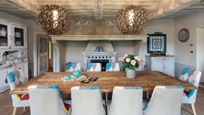Een eethoek met een houten tafel, stoelen met gestreepte kussens en twee hanglampen.