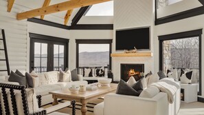 A modern living room with a fireplace, large windows, and a view of the outdoors. - Luxury Cabin Getaway in the Blue Ridge Mountains (Fort Valley)