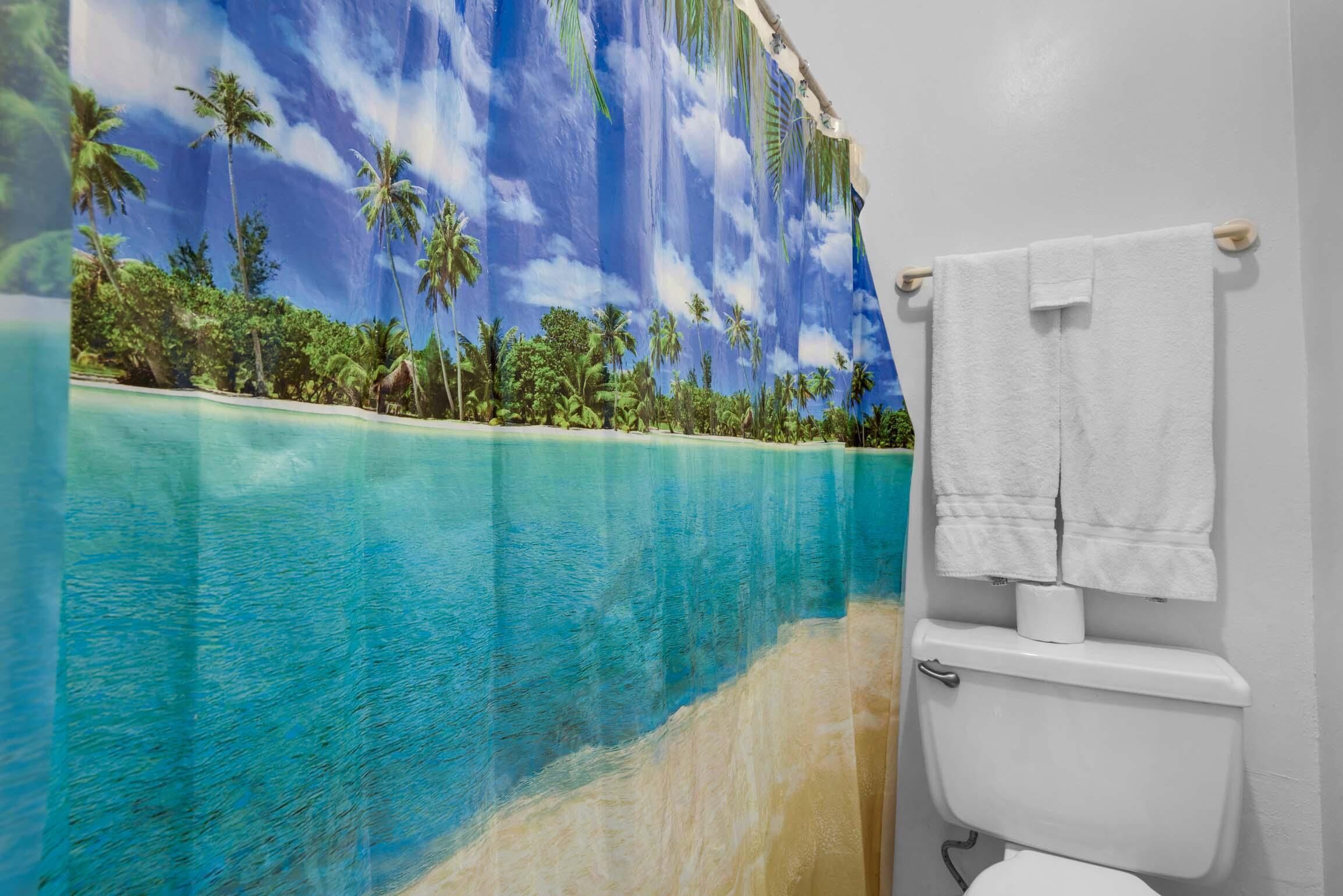 A bathroom with a tropical mural, a white toilet, and a towel rack.