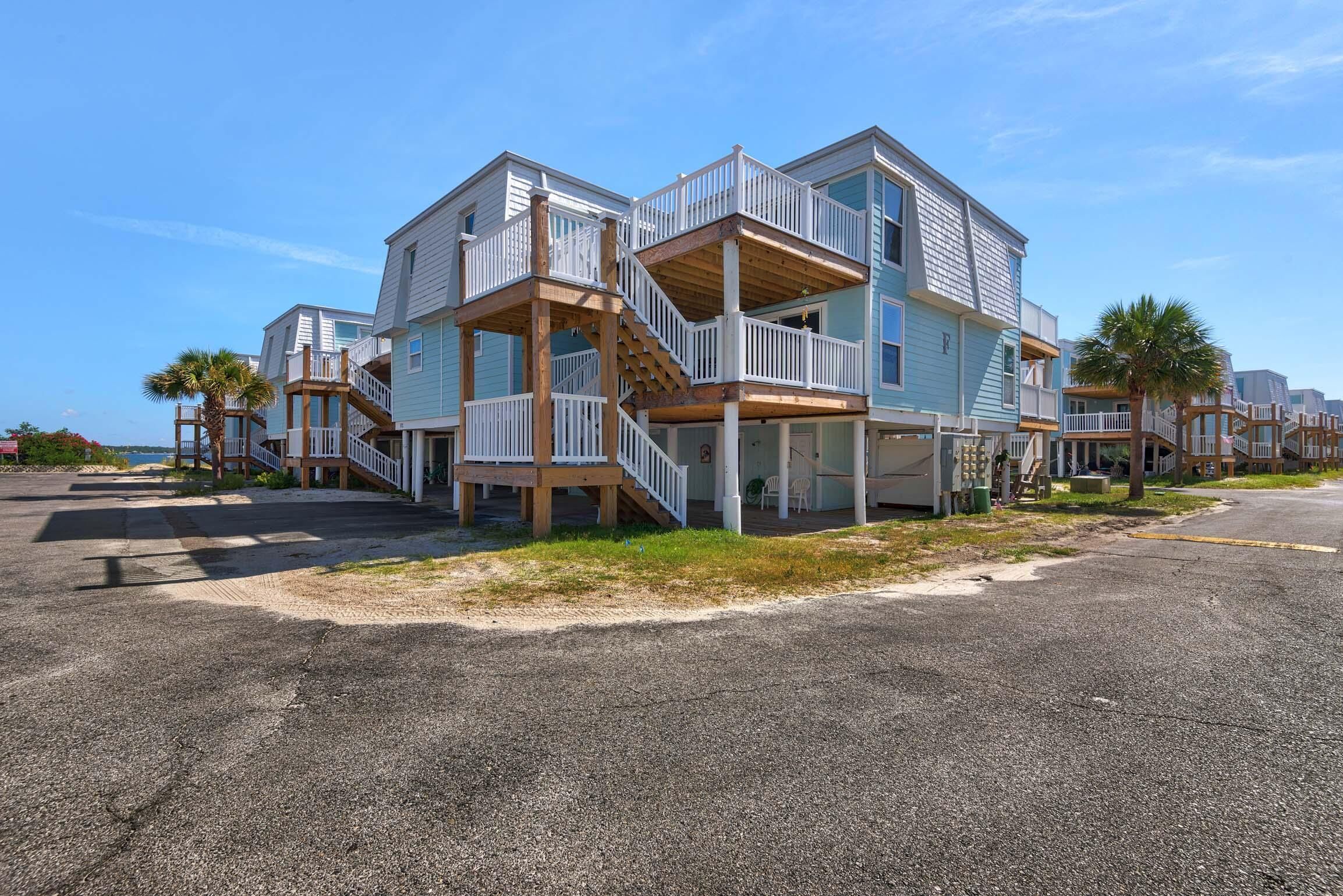 A beachfront property with multiple levels, wooden balconies, and a staircase leading to the upper floors.