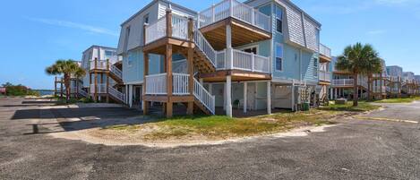A beachfront property with multiple levels, wooden balconies, and a staircase leading to the upper floors.