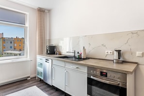 Una cocina moderna con horno integrado, cafetera y ventana con vista a edificios.