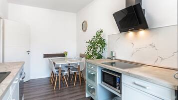 A compact kitchen with a built-in microwave, a stove, and a modern TV.