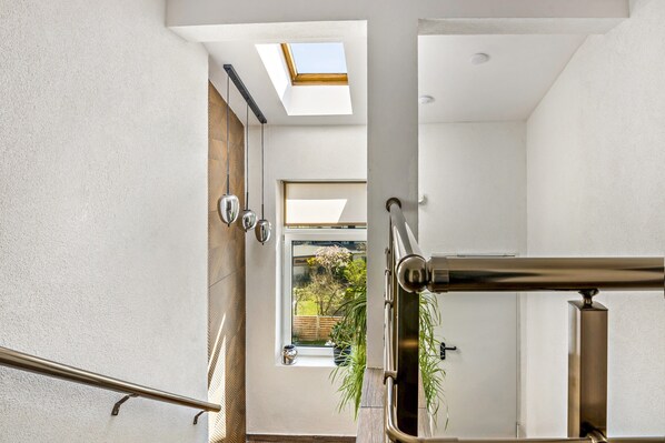 A modern interior with a skylight, a staircase, and a view of a garden.