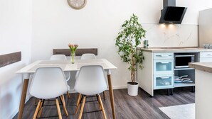Et moderne køkken med indbygget mikroovn, et vægur og en potteplante.