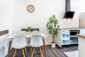 A modern kitchen with a built-in microwave, a clock on the wall, and a potted plant.