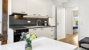 Een moderne keuken met witte kasten, een zwart aanrecht en een bloemenvaas op de tafel.
