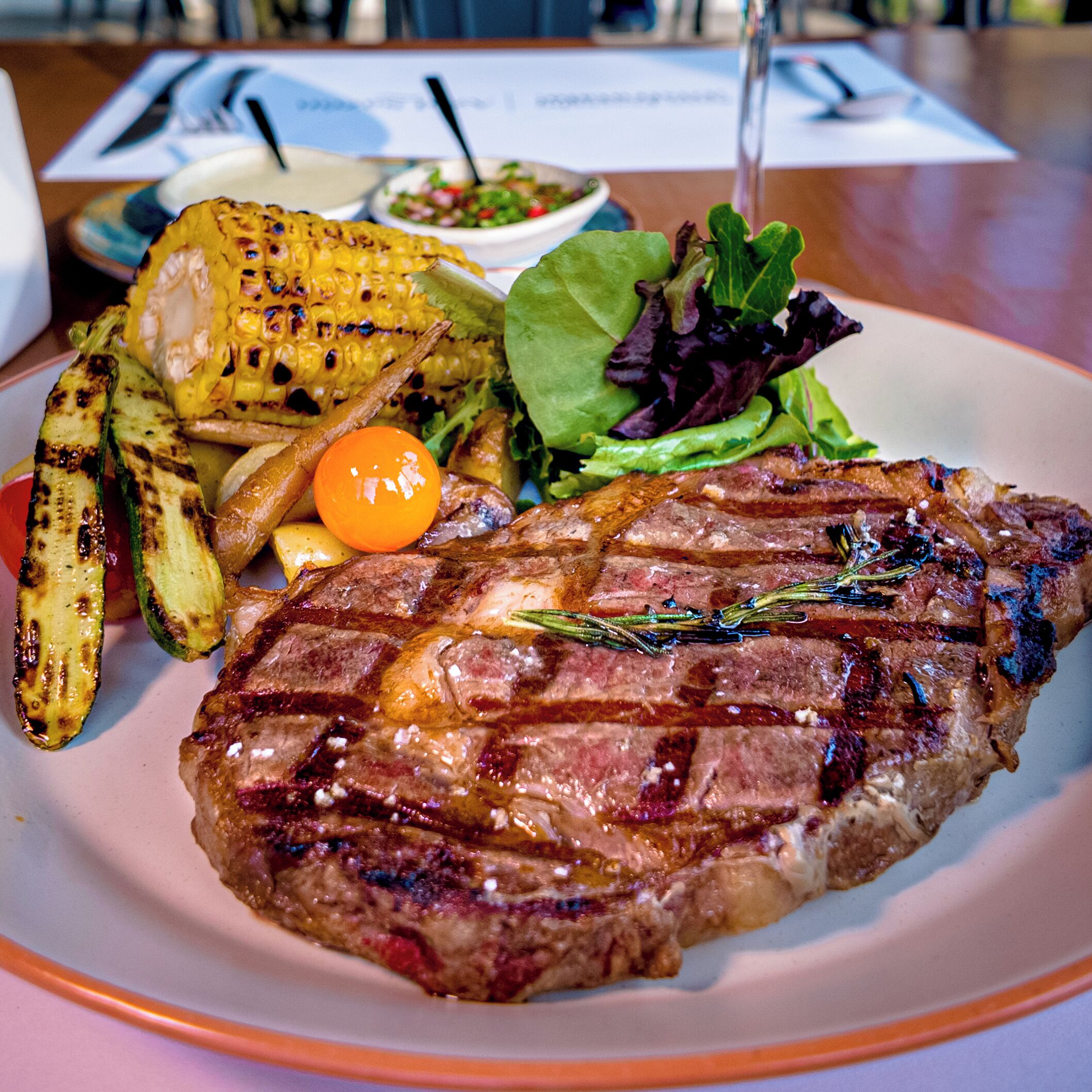 A plate with grilled steak, grilled vegetables, and a salad.