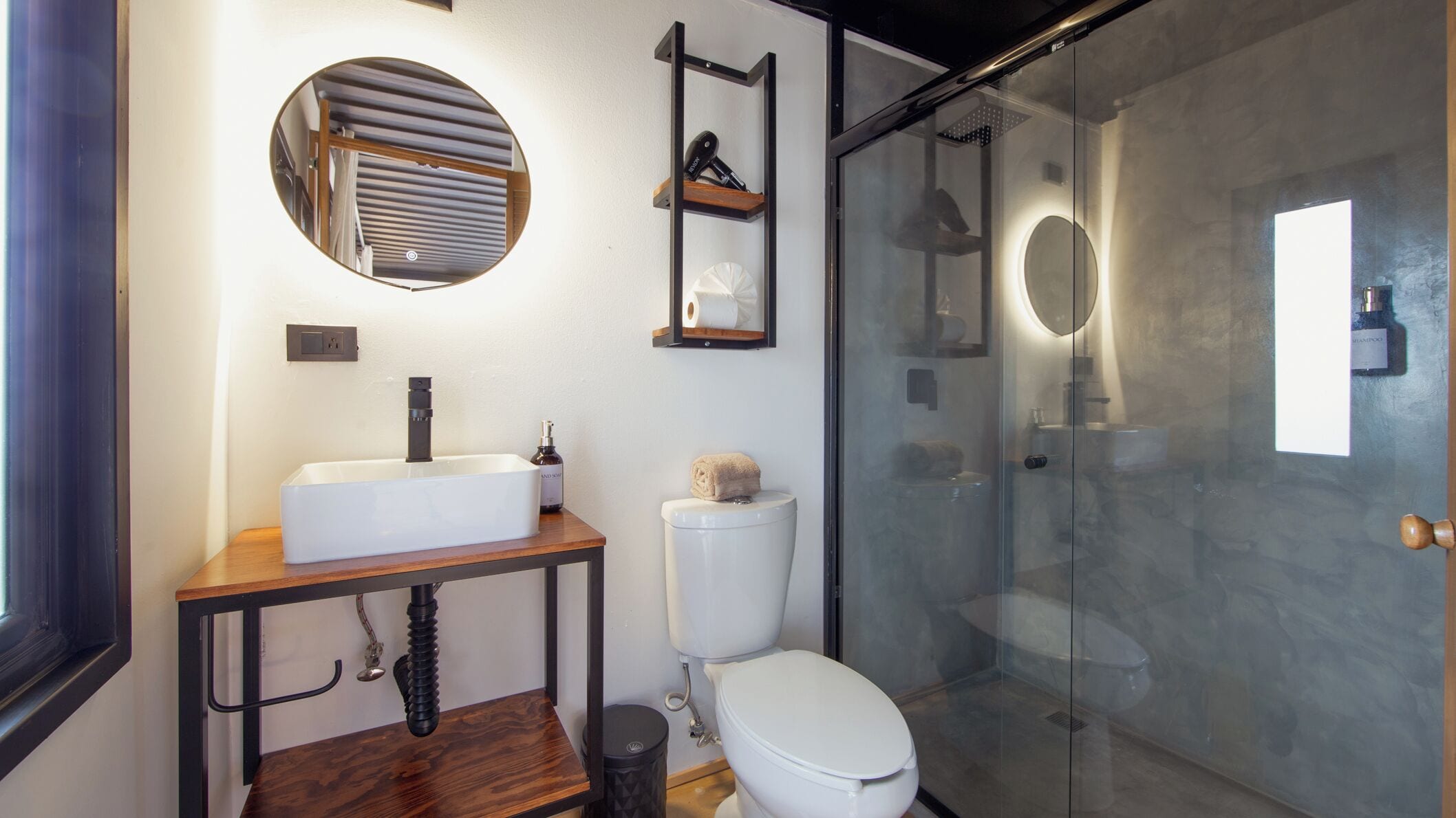 Un baño moderno con lavamanos, inodoro y cabina de ducha de vidrio.