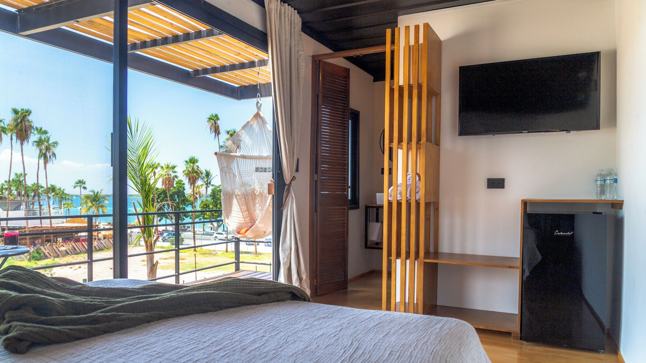 Un dormitorio con una cama grande, televisión y vista al mar.
