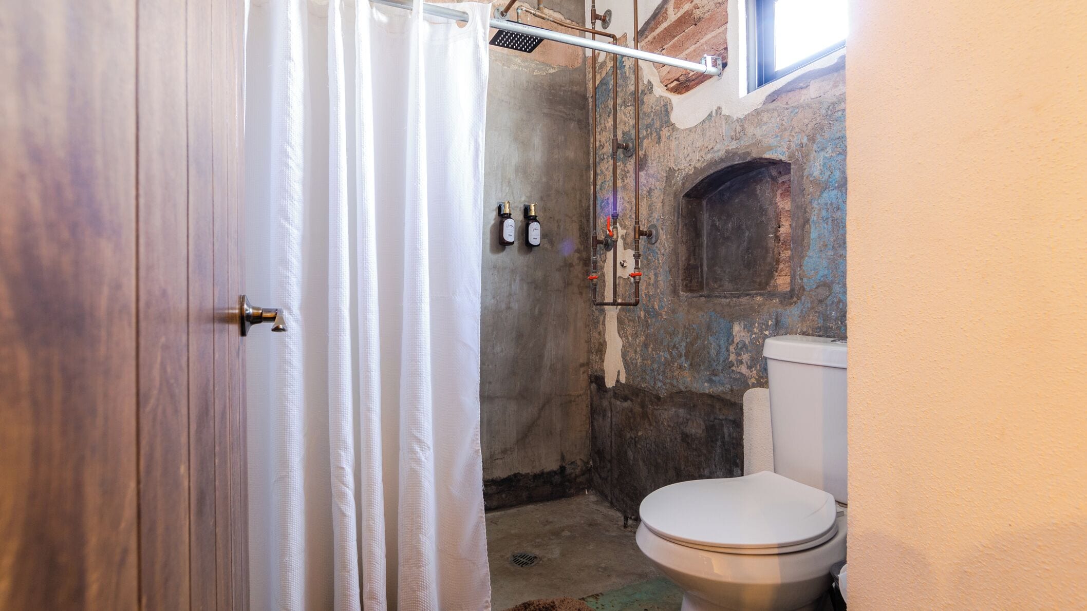 Ein Badezimmer mit Dusche, Toilette und Fenster.