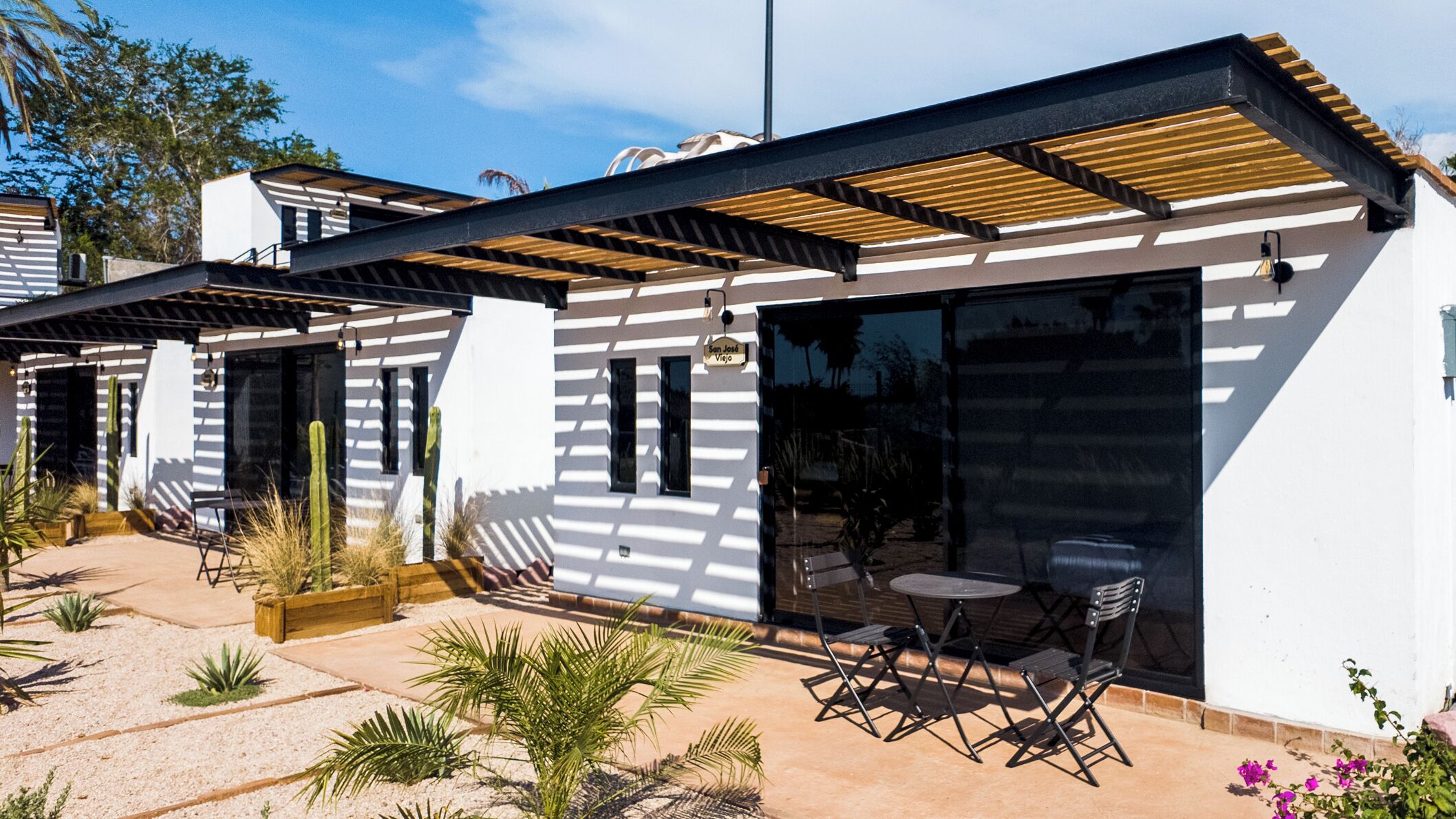 Una casa moderna con un patio amueblado y una pérgola.