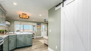 Una cocina con una isla grande, un comedor con vistas y una puerta corredera que conduce a una sala de estar.