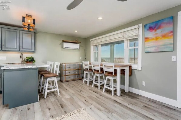 Une cuisine avec un coin repas, un plancher en bois et un ventilateur de plafond.