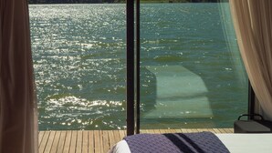 Une pièce dotée d’une grande fenêtre donnant sur un lac et des collines.