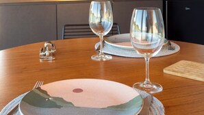 Une table de salle à manger en bois, mise avec des assiettes, des couverts et des verres à vin.
