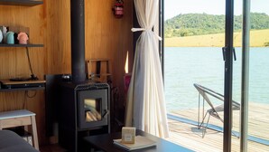Un chalet confortable avec un poêle à bois, une table à manger et une vue sur un lac.