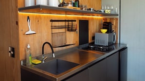 Une cuisine moderne dotée de meubles en bois, d’un évier en acier inoxydable, d’une machine à café et de divers ustensiles de cuisine.
