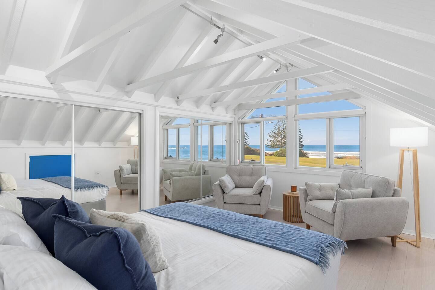 Wake up to sweeping ocean vistas in the primary bedroom, a spacious loft retreat with a king bed, cosy armchairs, and a bright, airy feel beneath vaulted ceilings.