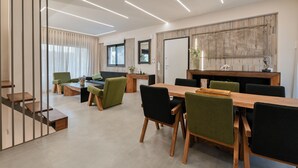 Una sala de conferencias moderna con una mesa de madera, sillas verdes y negras, y un amplio ventanal con cortinas.