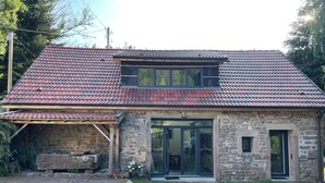 A stone house with a red-tiled roof, a wooden porch, and a gravel driveway. - Charming fully-equipped house (La Houssière)