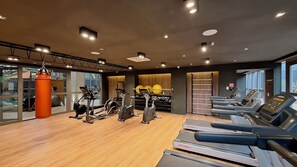 Un gimnasio con máquinas de cardio, equipo de pesas y un saco de boxeo.
