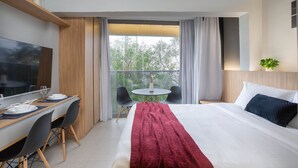 Et hotelværelse med seng, fjernsyn, et spisebord med stole og en balkon med bord og stole.