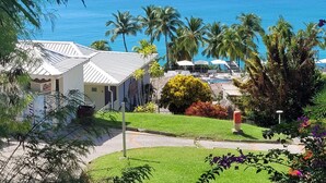 A coastal property with a swimming pool, palm trees, and a view of the ocean. - T2 Ti Madinina sea view with pool Le Diamant (Le Diamant)