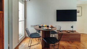 Un'area pranzo con un tavolo rotondo, quattro sedie e un televisore fissato alla parete.