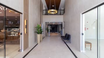 Um interior moderno com um corredor central, área de estar e portas de vidro que dão para um restaurante.