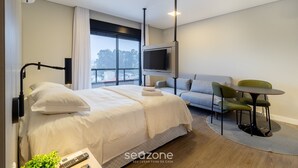 Una habitación de hotel moderna con una cama grande, un sofá, una mesita y un televisor.