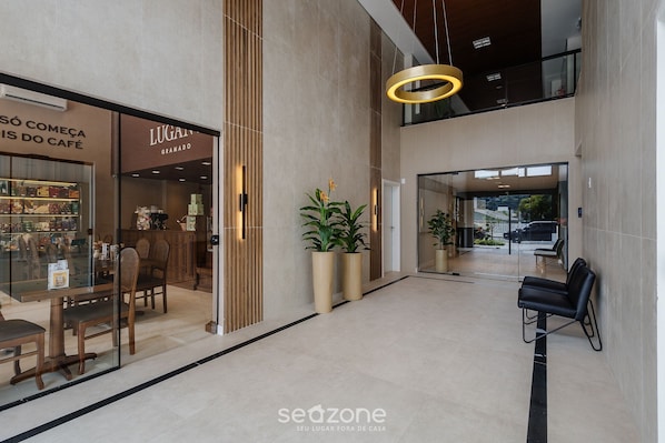 Un interior moderno con una cafetería, una zona de estar y una escalera.