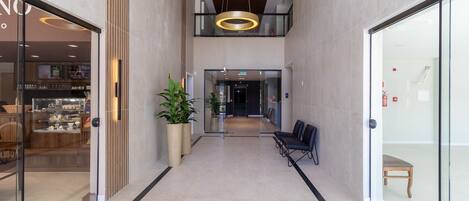 Un intérieur moderne avec un couloir central, un espace salon et des portes vitrées donnant sur un restaurant.