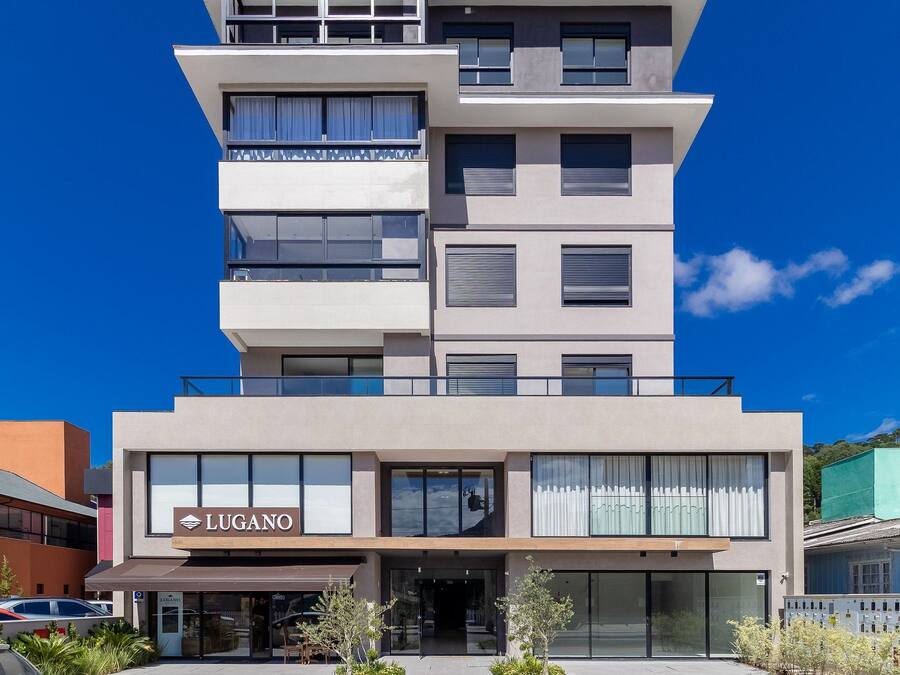 A multi-story hotel with a modern design, featuring a prominent 'LUGANO' sign at the entrance.