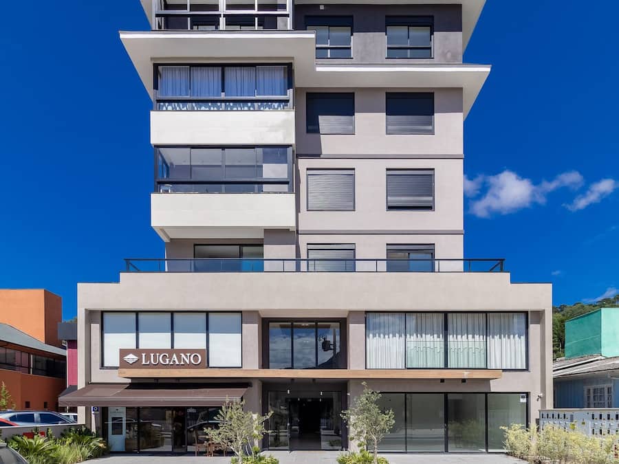 A multi-story hotel with a modern design, featuring a prominent 'LUGANO' sign at the entrance.
