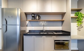 A compact kitchen with a stainless steel refrigerator, a built-in oven, and a coffee maker on a wooden shelf. - Your Perfect Stay in Urubici Starts Here! CZZ (Urubici)