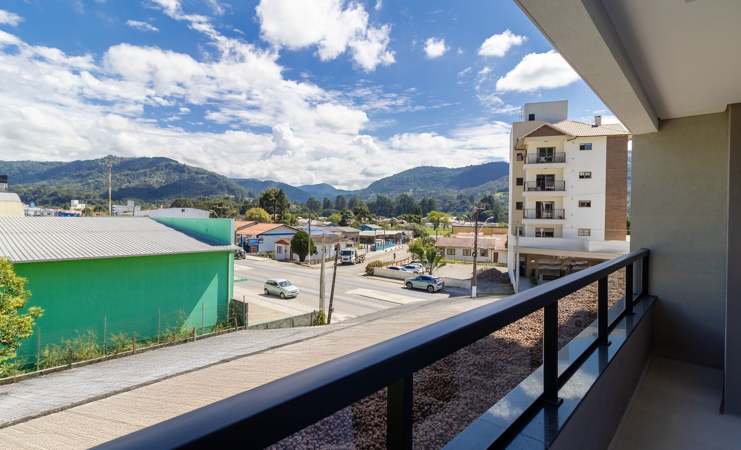 A balcony with a view of a town, buildings, and mountains.