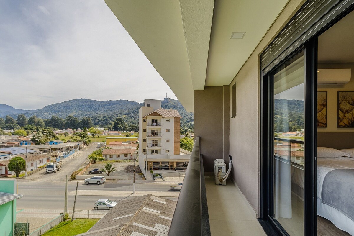 A balcony with a view of a residential area and mountains.