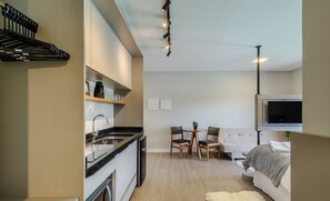 A modern kitchen with a dishwasher, a dining area with a table and chairs, and a bedroom with a bed and a TV. - Your Perfect Stay in Urubici Starts Here! CZZ (Urubici)