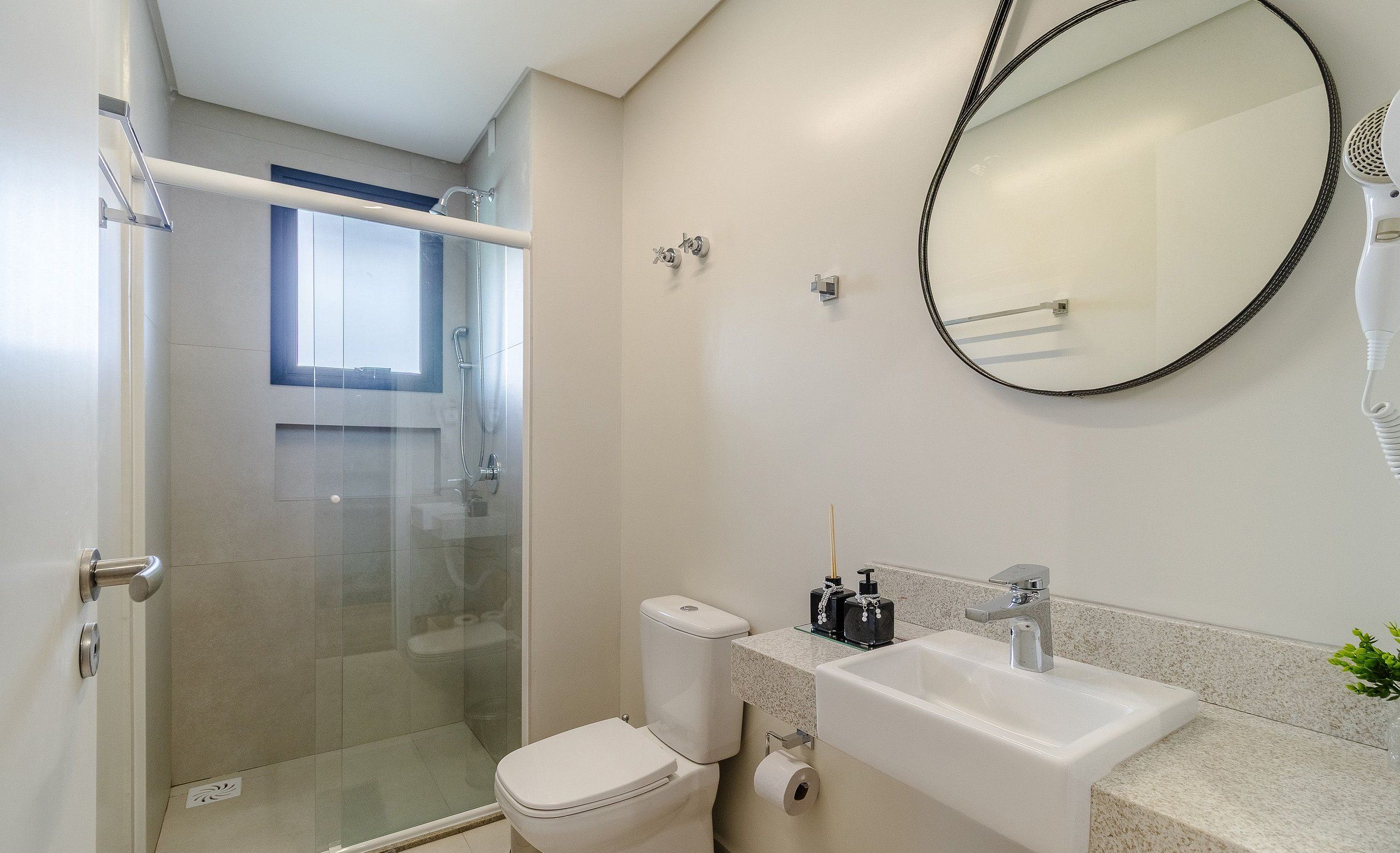 A modern bathroom with a glass shower enclosure, a toilet, and a sink with a mirror above it.