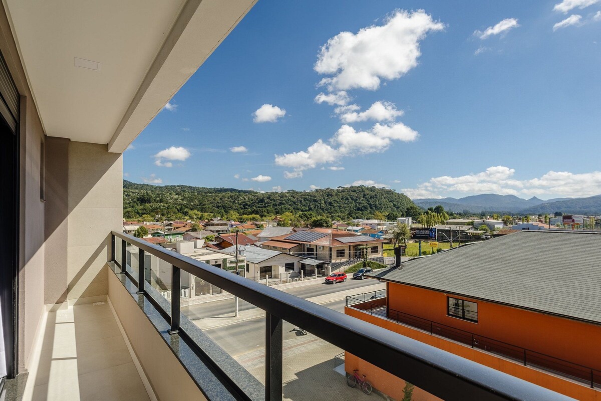 A balcony with a clear view of a town, including buildings and a hilly landscape in the distance.