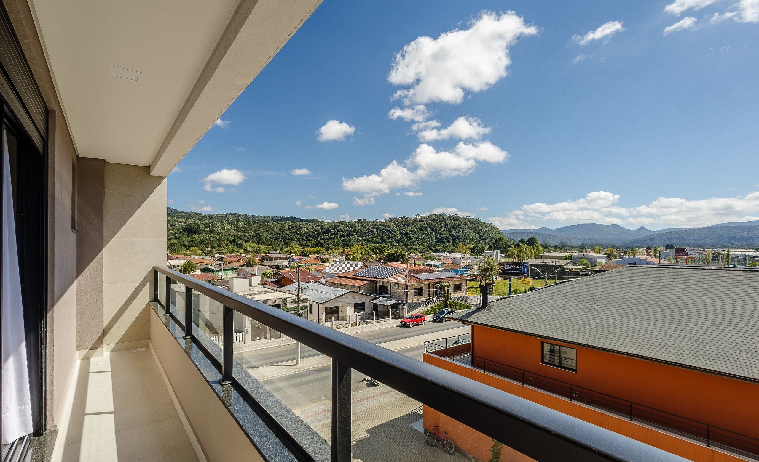 Ein Balkon mit freiem Blick auf eine Stadt, einschließlich Gebäude und einer hügeligen Landschaft im Hintergrund.