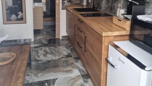 Una cocina moderna con armarios de madera, salpicadero de mármol y horno empotrado.