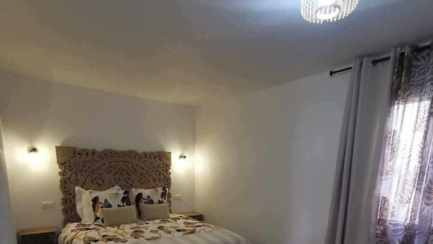 Un dormitorio moderno con una cama grande, un cabecero decorativo y una araña.