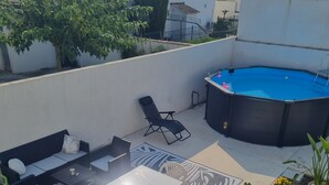 Terraza en la azotea con piscina, mobiliario exterior y plantas en macetas.